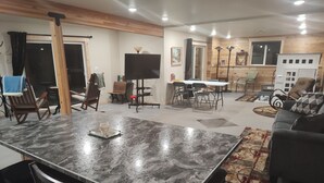 Un vaste espace de vie comprenant une grande table en marbre, des chaises en bois, un canapé et une table à manger avec des chaises.