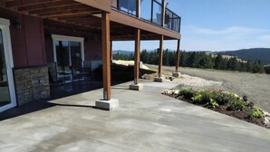 Un bâtiment moderne doté d’un espace extérieur couvert, de murs en pierre et offrant une vue sur le paysage environnant.