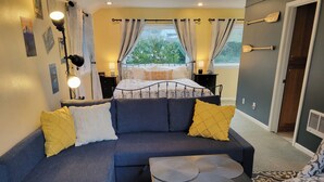A modern living room with a sofa, a coffee table, and a bed with a view of the outdoors. - All the amenities of home with no cleaning fees and first breakfast included!  (West Linn)