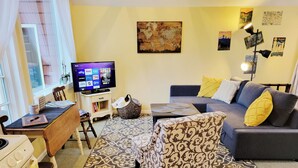A living room with a sofa, armchair, and a television displaying streaming services. - All the amenities of home with no cleaning fees and first breakfast included!  (West Linn)