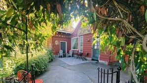 A red building with a patio area, a black gate, and a red chair. - All the amenities of home with no cleaning fees and first breakfast included!  (West Linn)