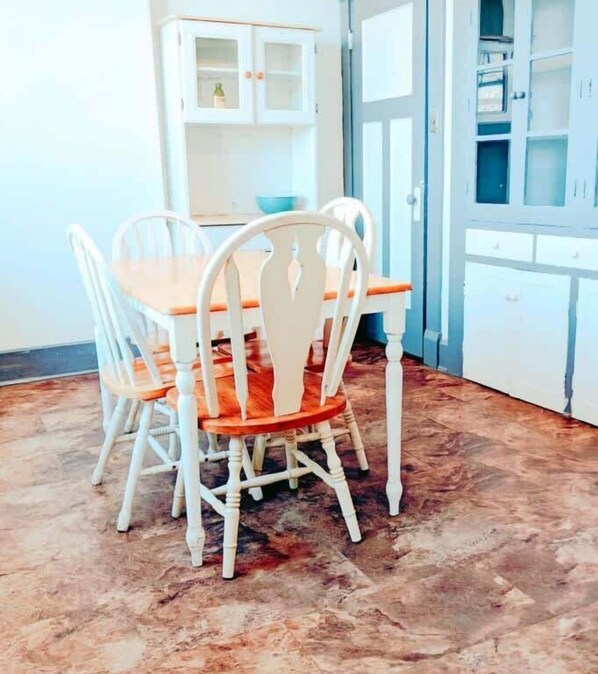 A dining area with a table and four chairs, a cabinet with glass doors, and a patterned floor.