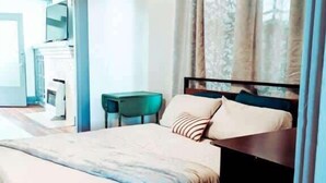 Ein modernes Schlafzimmer mit einem großen Bett, einem kleinen Tisch und einem an der Wand befestigten Fernseher.