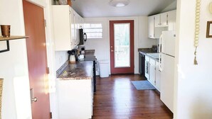 A kitchen with white cabinets, a wooden countertop, and a door leading to a balcony. - Cape Town Cottage 3 Blocks From Oaklawn (Hot Springs)