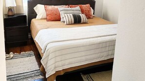 A bedroom with a bed, a nightstand, a lamp, a ceiling fan, and a window with curtains. - Cape Town Cottage 3 Blocks From Oaklawn (Hot Springs)