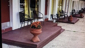 A hotel entrance with outdoor seating and a large terracotta planter with flowers. - Unit 12*King Bedroom, Mini Fridge, Wifi, Tv (Hot Springs)