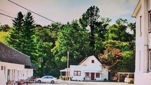 A street view with a white building with a porch and a car parked in front. - Unit 12*King Bedroom, Mini Fridge, Wifi, Tv (Hot Springs)