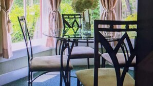 A room with a large window, curtains, a table with chairs, and a vase with flowers. - Unit 14 Roomy King Suite With Daybed Kitchenette, (Hot Springs)