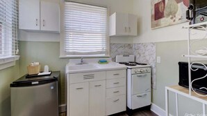 A compact kitchen with white cabinets, a stove, and a refrigerator. - Unit 14 Roomy King Suite With Daybed Kitchenette, (Hot Springs)
