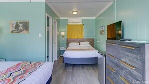 Et hotelværelse med en seng, en kommode, et fjernsyn og et maleri på væggen.