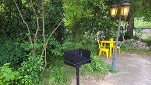 Un barbecue dans un espace jardin, avec des chaises jaunes et un lampadaire.