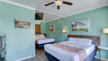 A hotel room with two beds, a ceiling fan, and artwork on the walls.