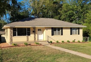 A single-story house with a front porch, a small front yard, and a garage.