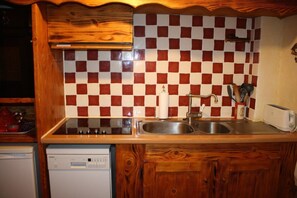 Uma cozinha com azulejos xadrez, armários de madeira, uma pia de aço inoxidável, uma torradeira e uma máquina de lavar louça.