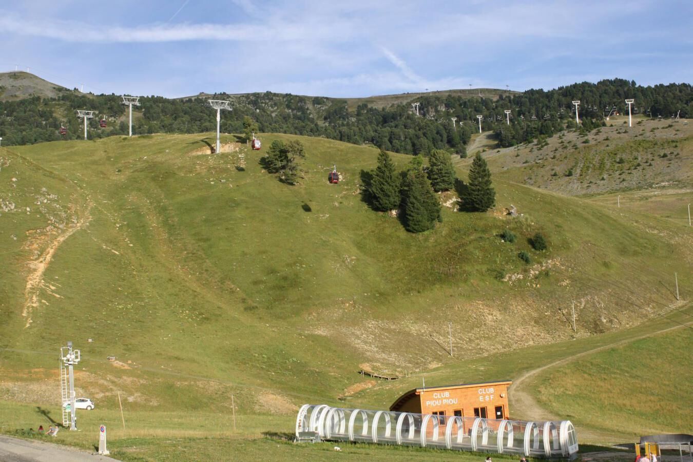 A hilly landscape with a ski lift, a small building labeled 'CLUB PIEDU PIOU,' and a covered walkway.