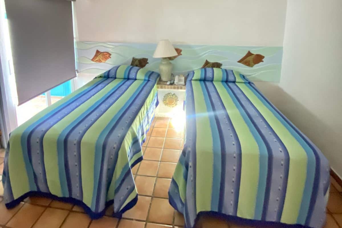 A room with two beds, a TV, and a ceiling fan.