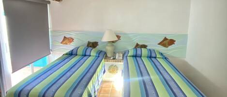 A room with two beds, a TV, and a ceiling fan.