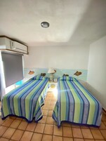Una habitación con dos camas, televisión y ventilador de techo.