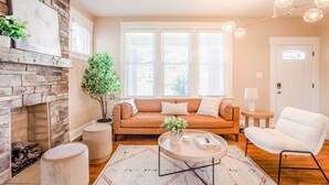 Ein Wohnzimmer mit Kamin aus Stein, einer Couch, einem Couchtisch und einem weißen Sessel.