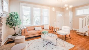 Ein geräumiges Wohnzimmer mit Sofa, Sesseln, Couchtisch und Kamin.