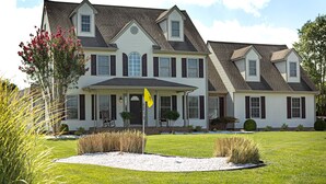 A large, two-story house with a symmetrical facade, multiple windows, and a front porch.