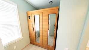A room with a wooden wardrobe, a mirror, and a window with blinds.