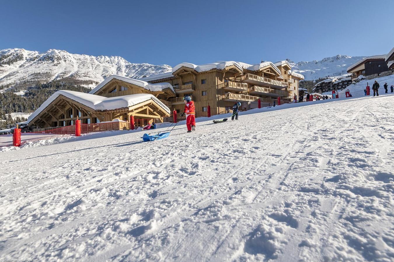 Une station de ski avec des bâtiments en bois, un télésiège et une montagne enneigée en toile de fond.
