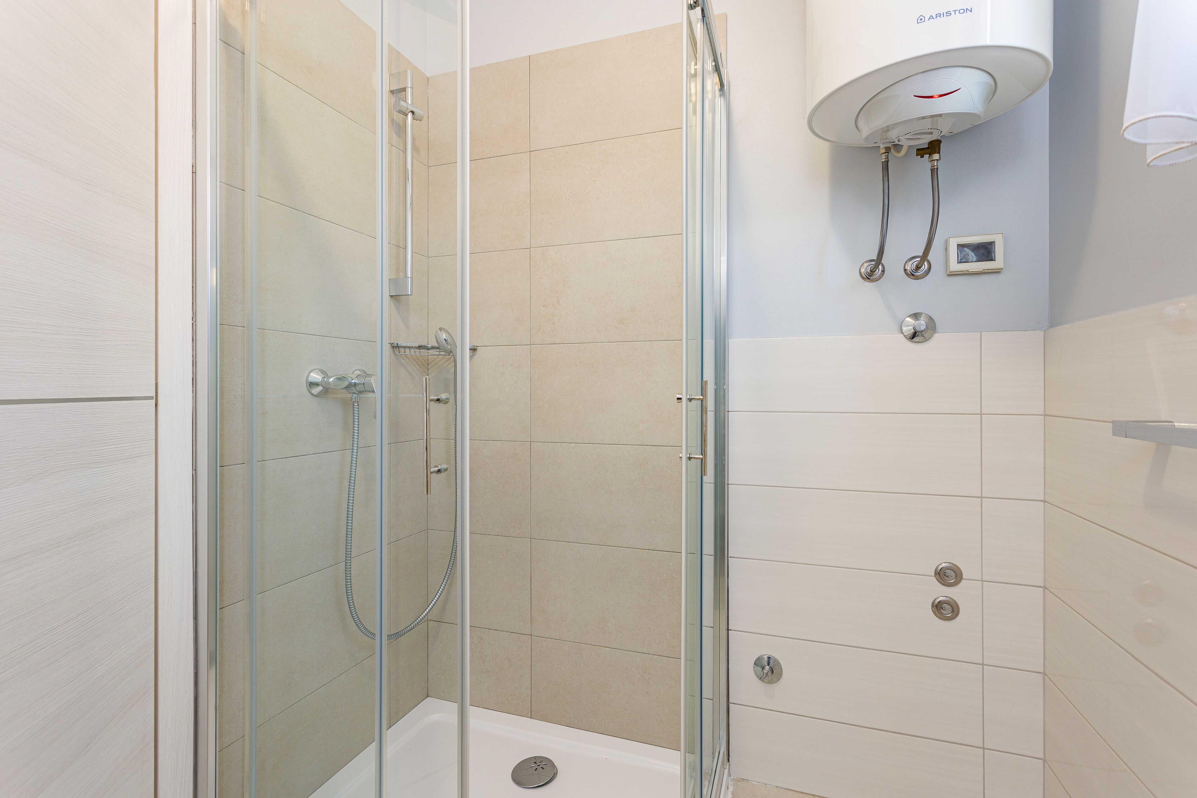 Ein modernes Duschbad mit Glasabtrennung, Wandheizung und Bedienfeld.