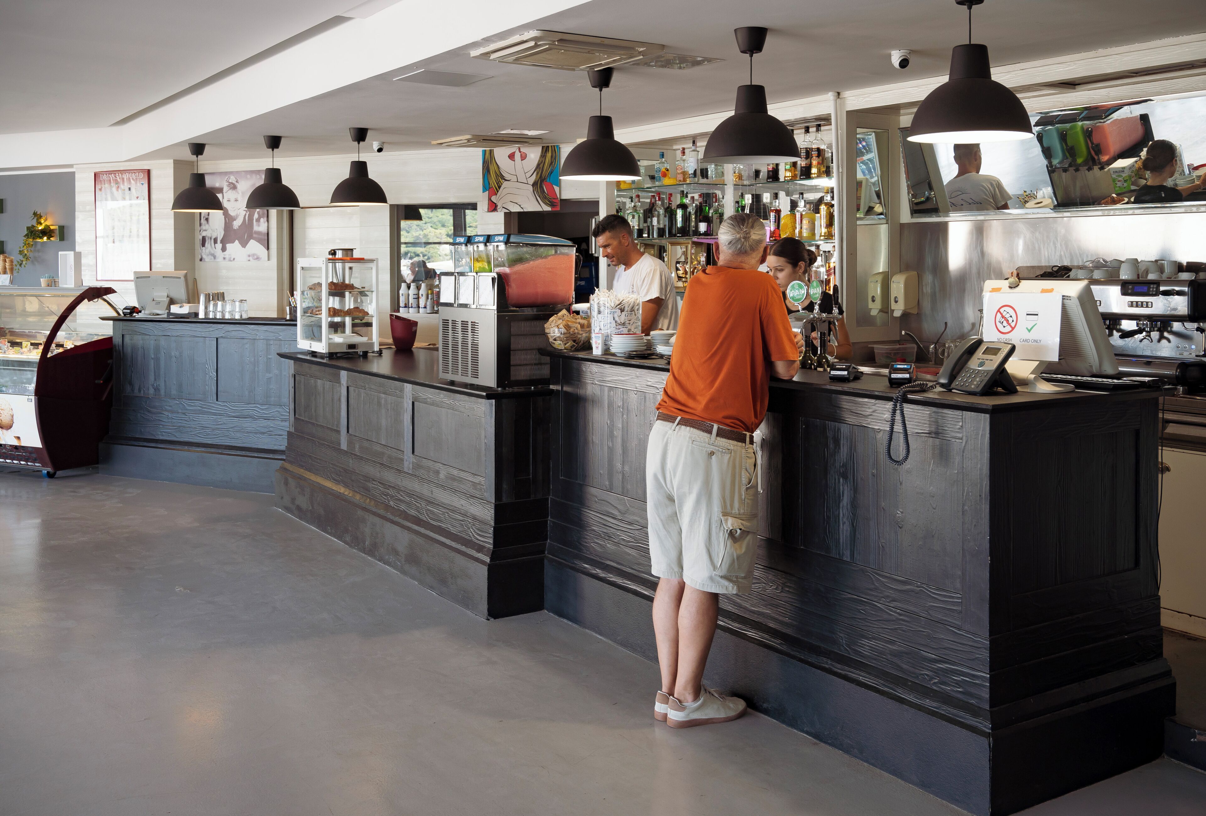 Uma área de bar moderna com balcão, banquetas e iluminação pendente.