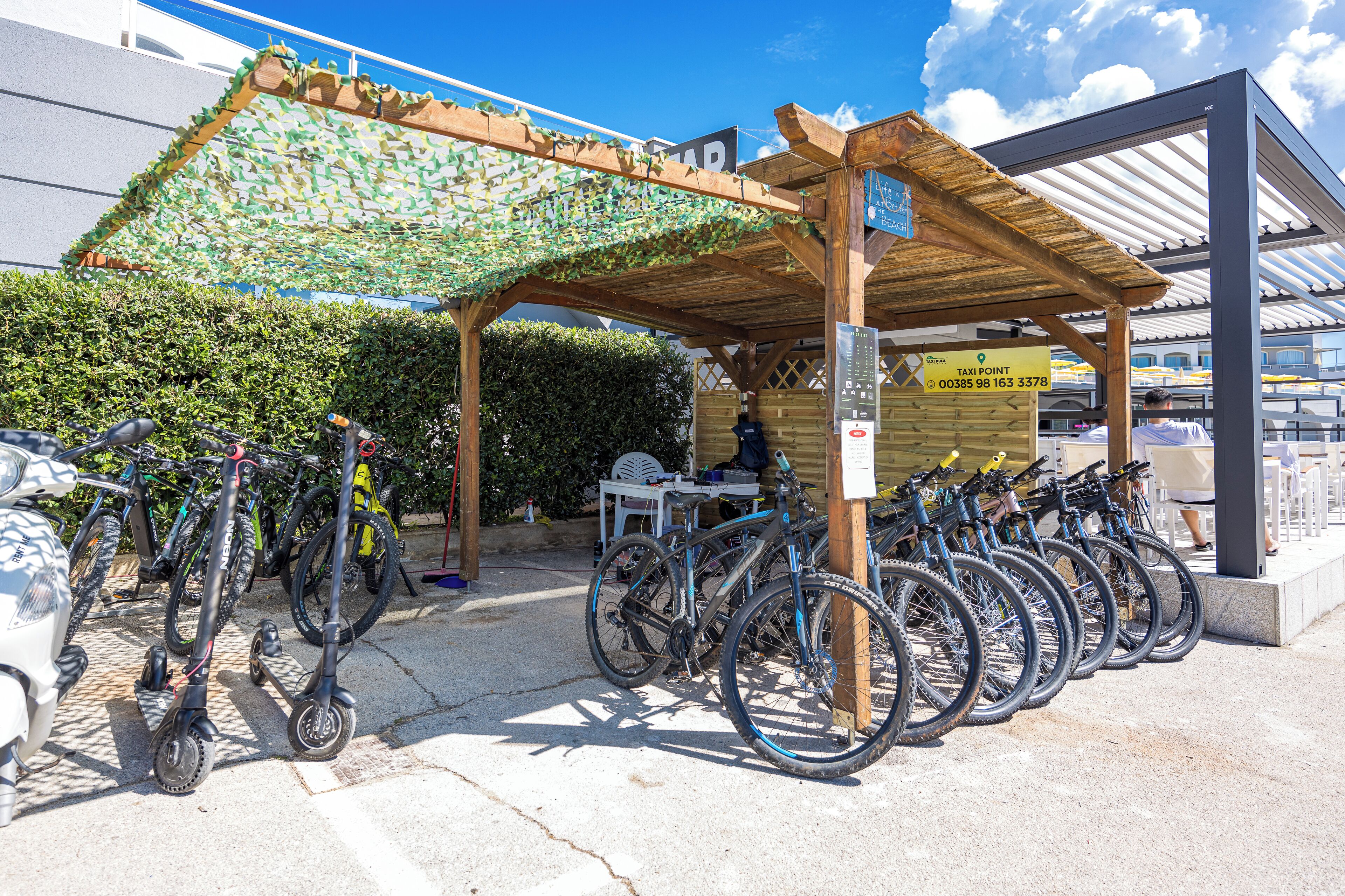 A bike rental station with multiple bicycles and a sheltered seating area.