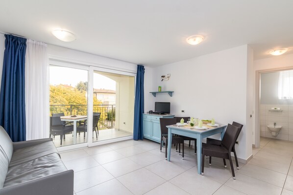 A modern apartment with a balcony, a dining area, a sofa, and a kitchenette. - Residence Superior Del Mar (Medulin)