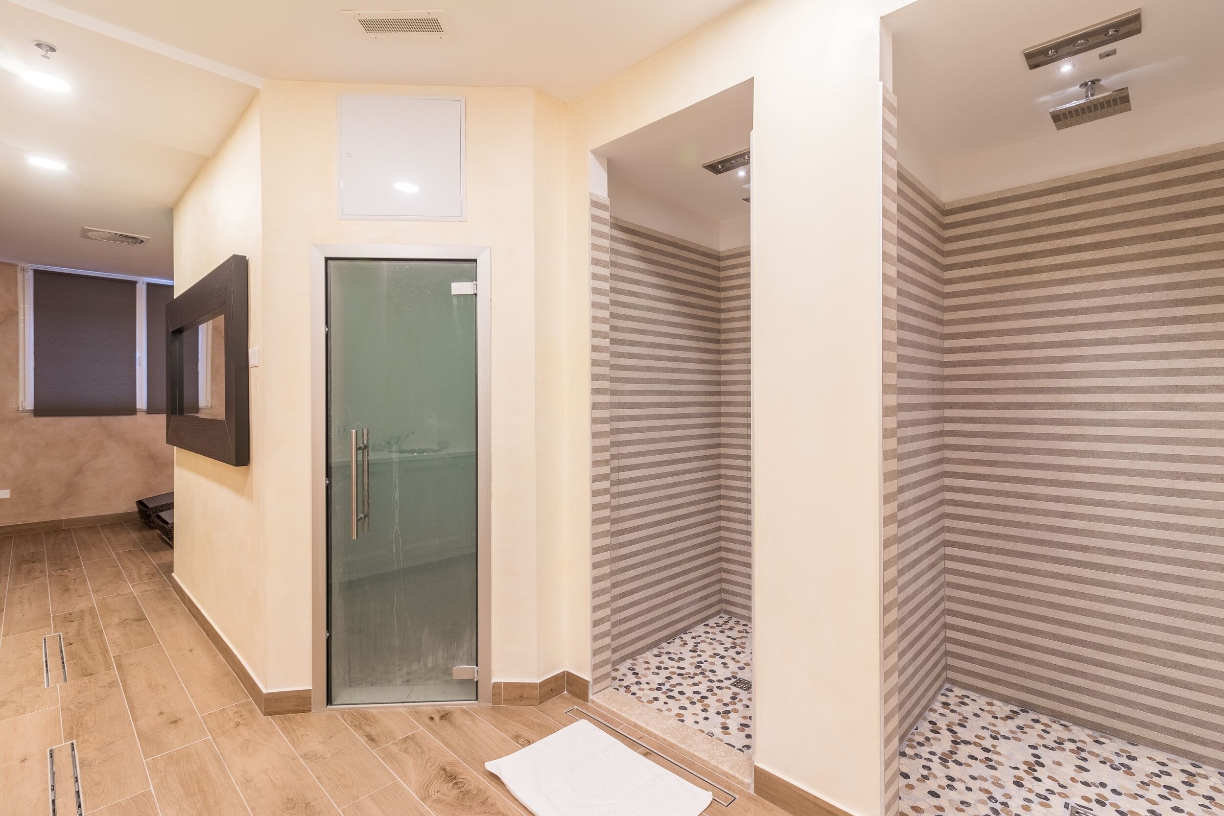 A modern bathroom with a glass shower door, striped shower walls, and a tiled floor.