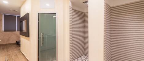 A modern bathroom with a glass shower door, striped shower walls, and a tiled floor.