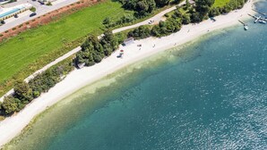 An aerial view of a beach with a clear path, a small structure, and a boat dock.