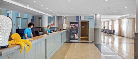 Un'area reception di un hotel con un bancone, una decorazione di un polpo in velluto e un cartello pubblicitario per un servizio spa.