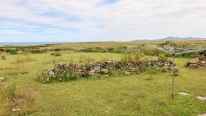 A rural landscape with a stone wall, grassy fields, and distant hills. - Chalfonts Cottage (Haverfordwest)