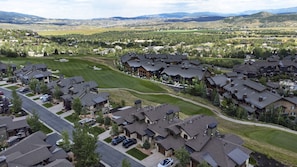 Zona residencial com casas modernas, gramado bem cuidado e uma cordilheira ao longe.
