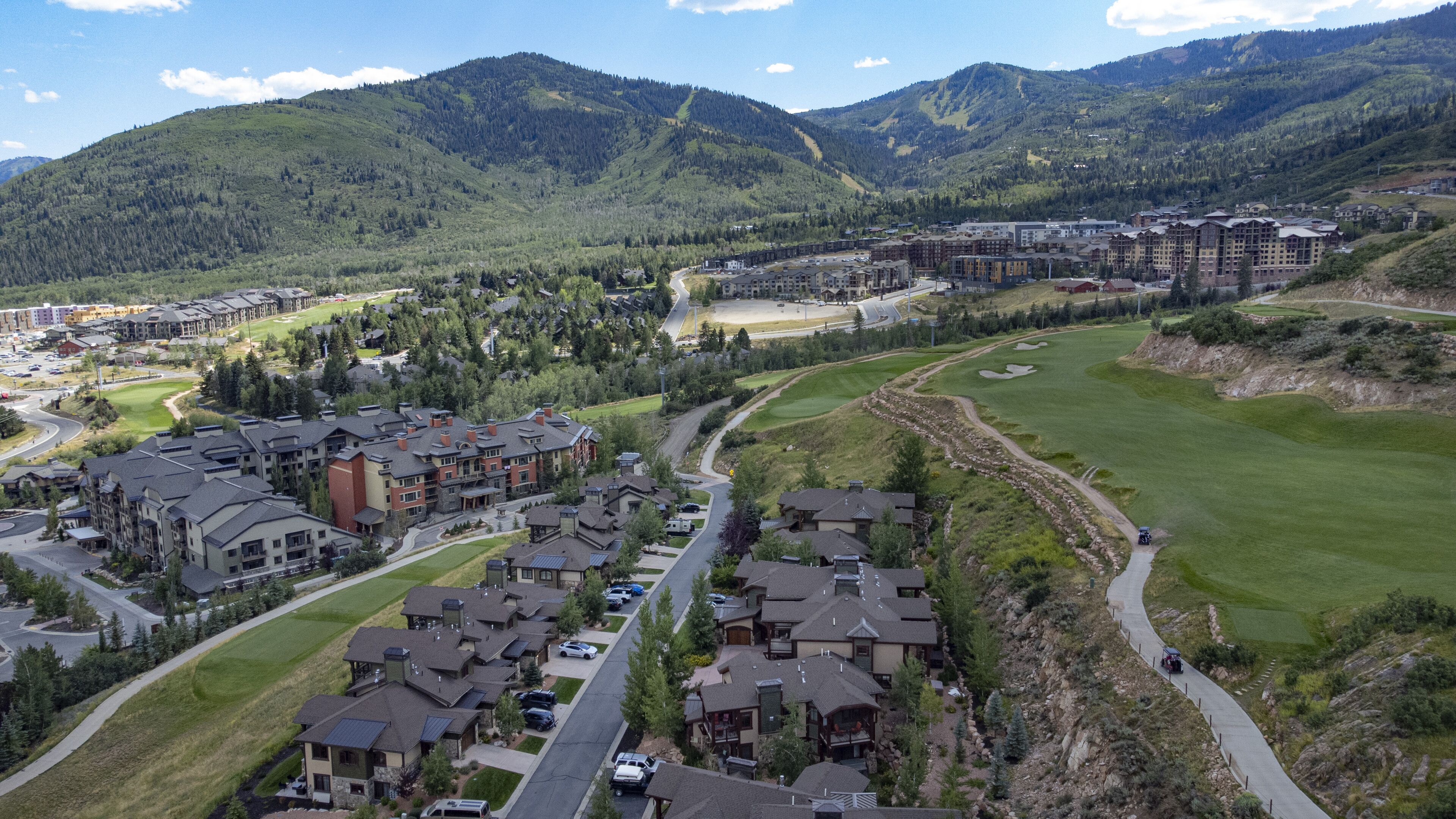 Un quartier résidentiel composé d’immeubles à plusieurs étages, d’un terrain de golf et bordé de montagnes.