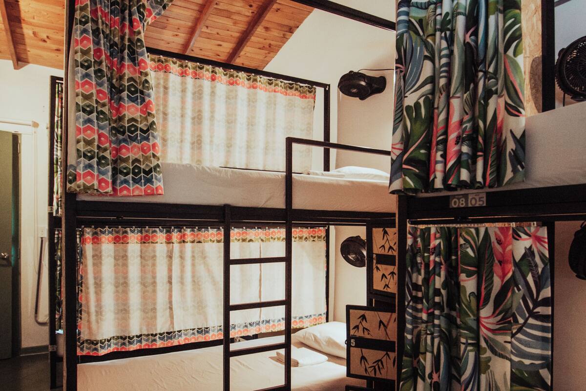 Quarto com beliche, teto de madeira e vista para o céu.