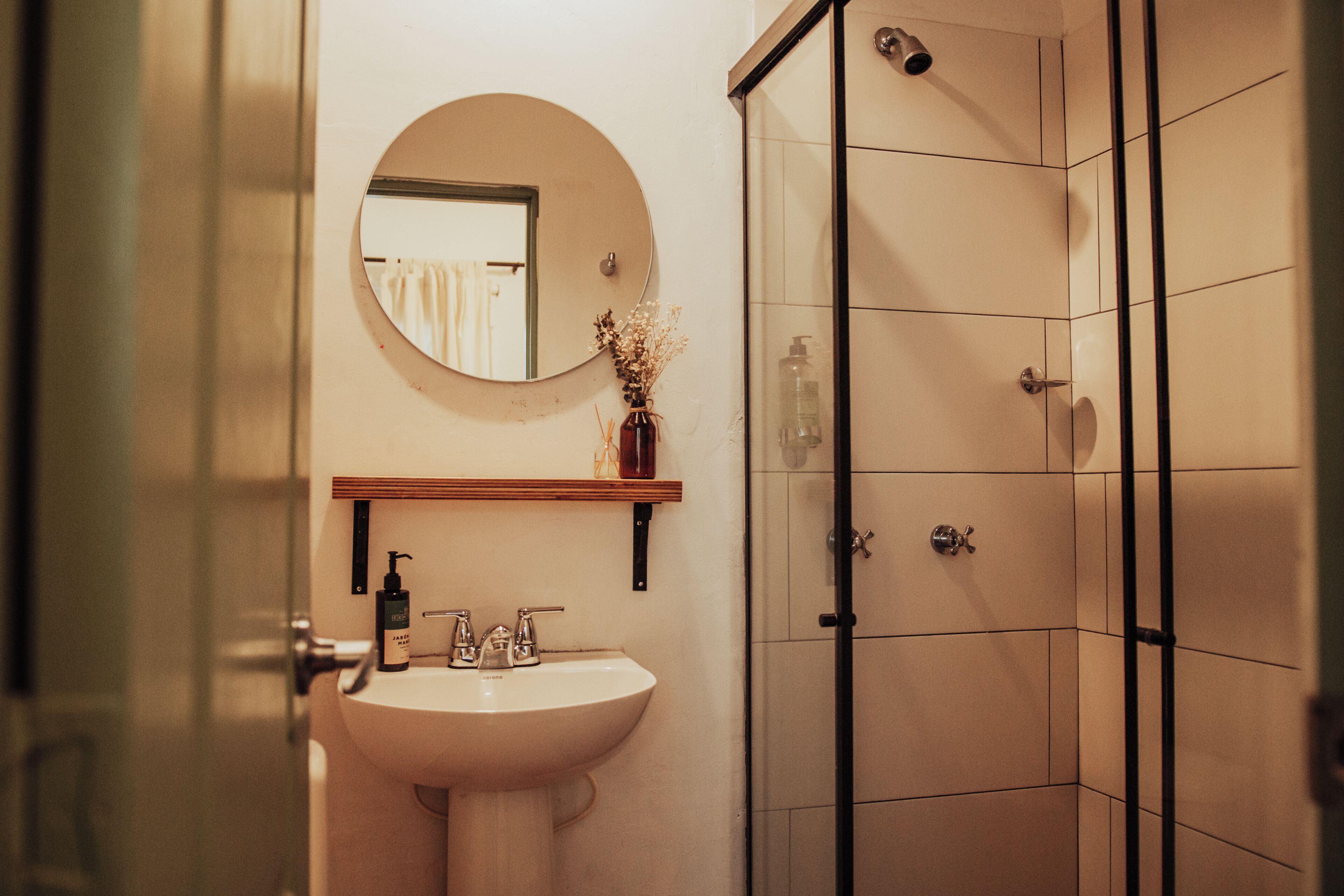 A bathroom with a sink, mirror, and shower.