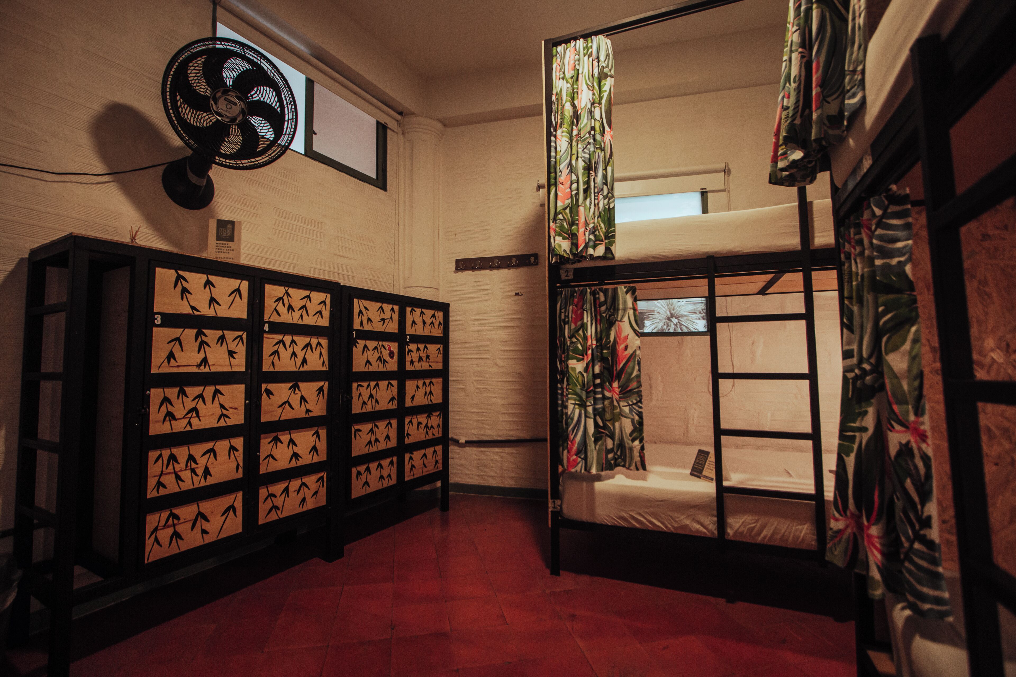 A room with bunk beds, a fan, and a cabinet with bamboo designs.
