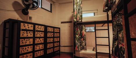 A room with bunk beds, a fan, and a cabinet with bamboo designs.