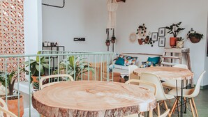 A dining area with a round wooden table and chairs, a high ceiling with exposed beams, and a view of the sky through a skylight. - Centro Hostel Medellín (Medellín)