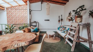 A cozy patio area with a round wooden table, white chairs, a sofa with colorful cushions, and a wooden ladder. - Centro Hostel Medellín (Medellín)