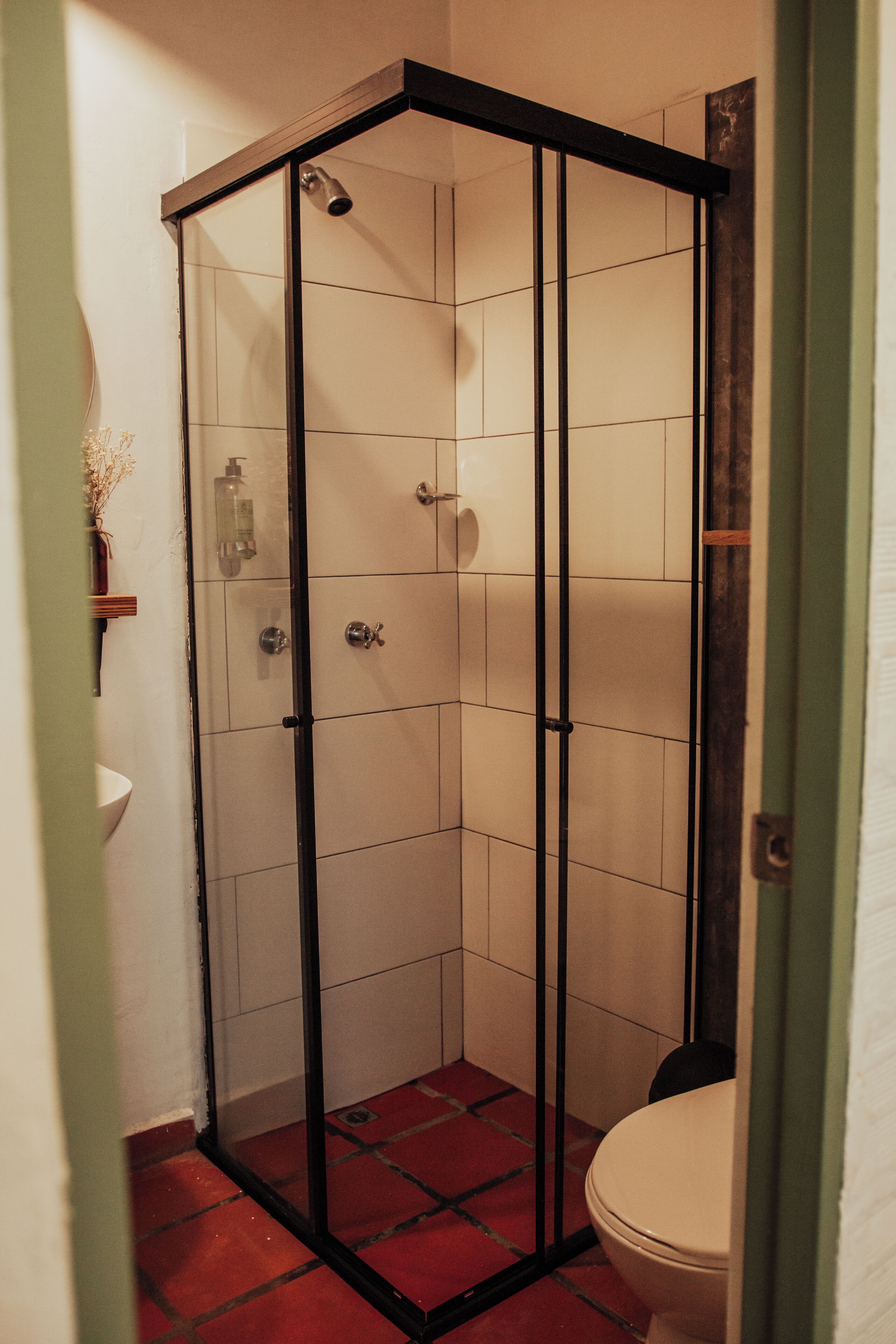 A bathroom with a glass-enclosed shower, a toilet, and a sink.
