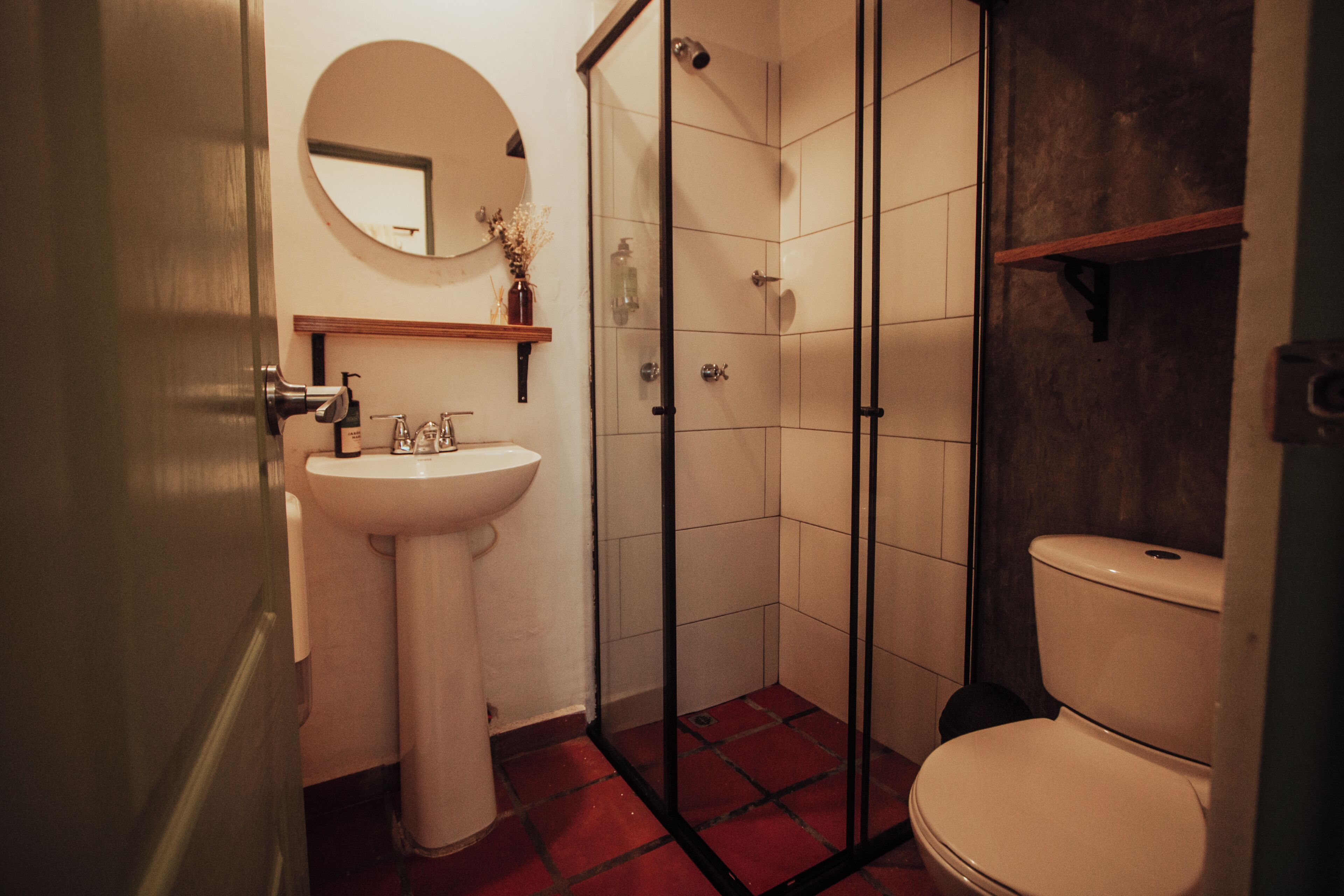 Un baño con lavamanos, inodoro y ducha con mampara de vidrio.