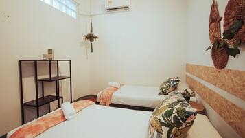 A hotel room with two beds, a shelf unit, an air conditioning unit, and a window.