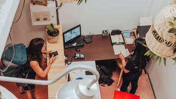 Ein moderner Arbeitsplatz mit Schreibtisch, Computer und zwei arbeitenden Personen.