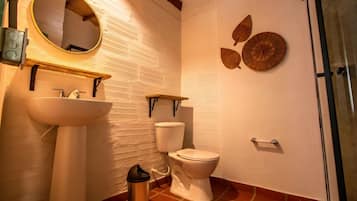 A bathroom with a white sink, a toilet, a mirror, and decorative wall art.