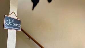 A wall with a world map and a 'Welcome Please Remove Your Shoes' sign. - Comfy & spacious home (Austin)